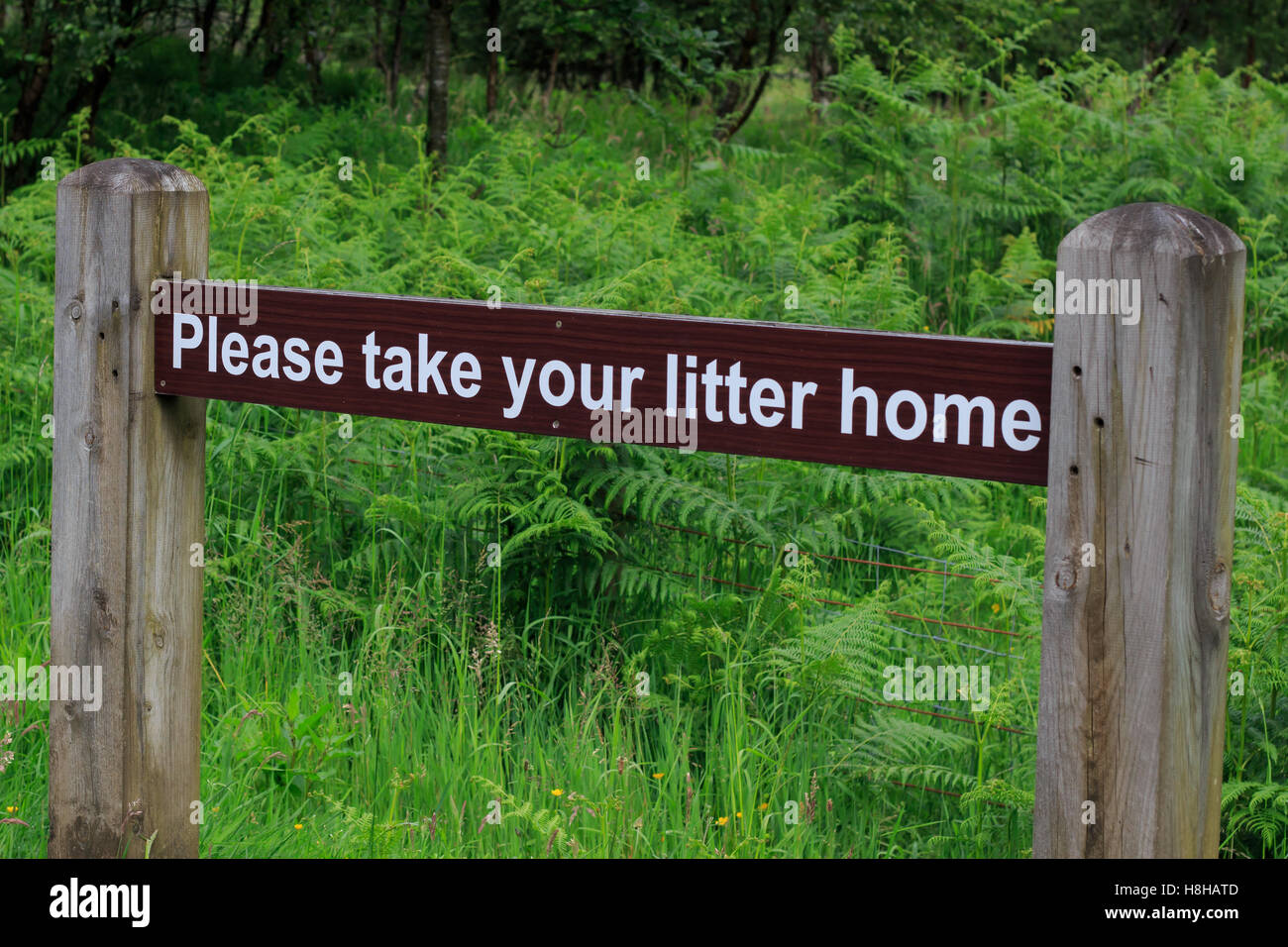 Wooden countryside  brown sign  board with white letting requesting Please Take Your Litter Home Stock Photo
