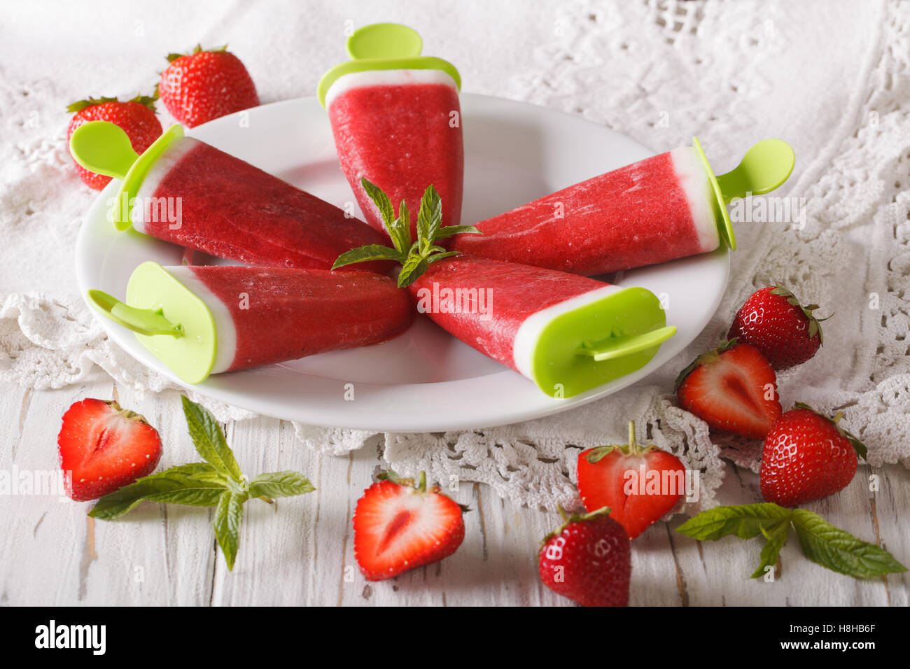 Strawberry ice cream with mint and yogurt on a stick closeup on a plate. horizontal Stock Photo