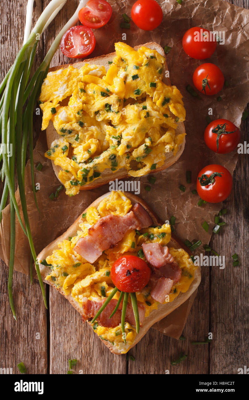 Homemade sandwich with scrambled eggs, bacon and tomatoes close-up on