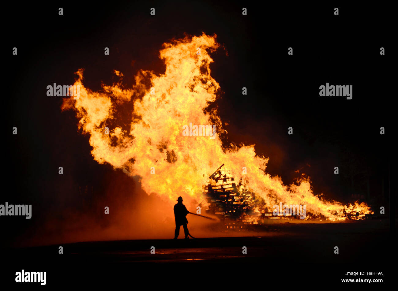 Fireman dousing bonfire Stock Photo