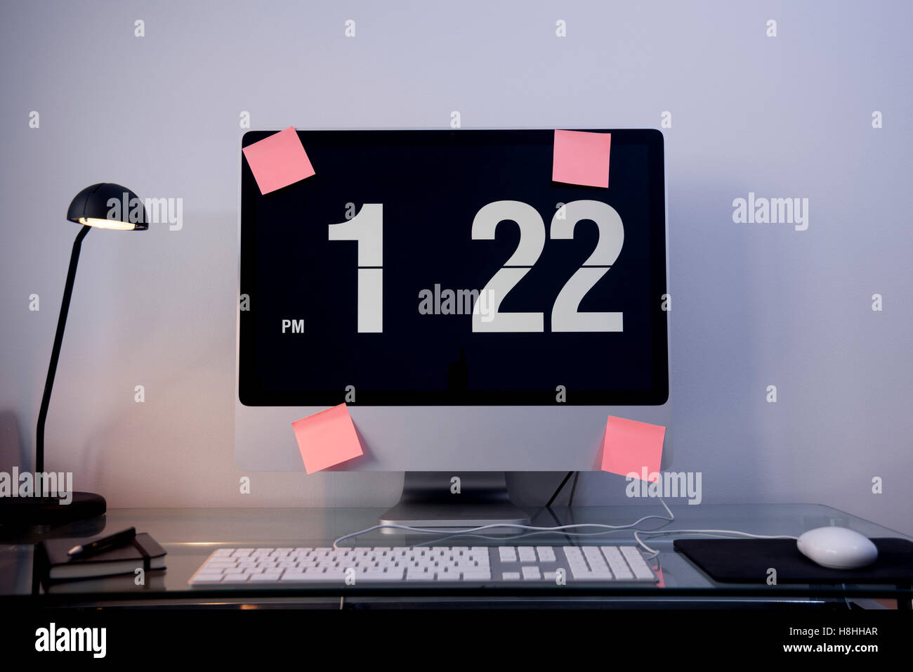 modern flat screen computer on a glass desk with time on the screen ...