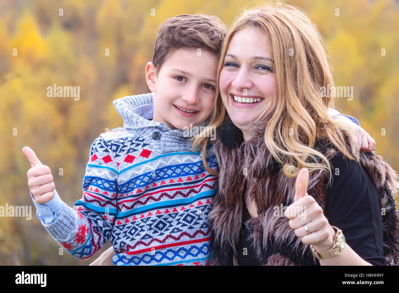 Mother and son showing ok sign stand outdoors in nature Stock Photo