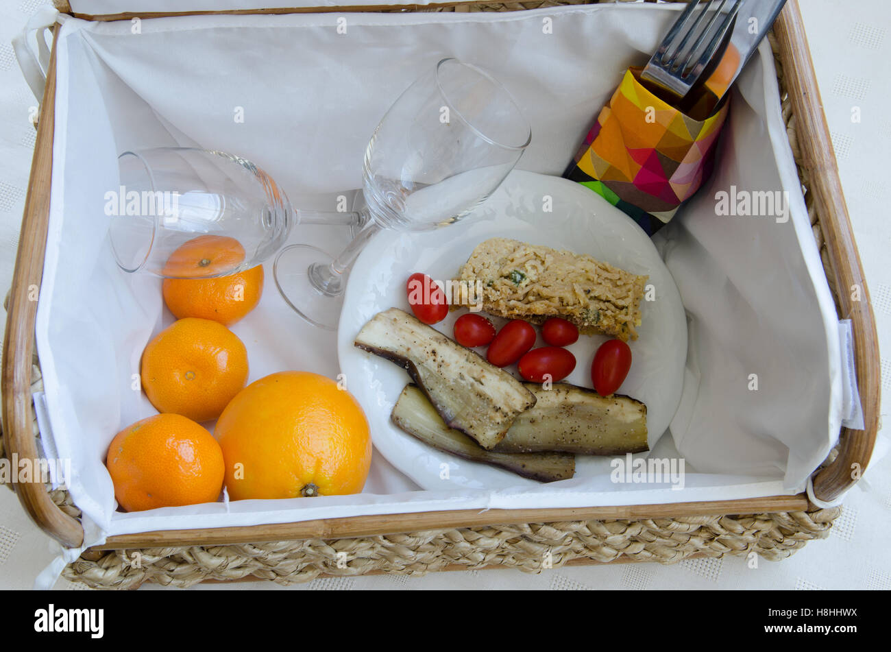 Picnic basket with wine glasses, fruit and food Stock Photo