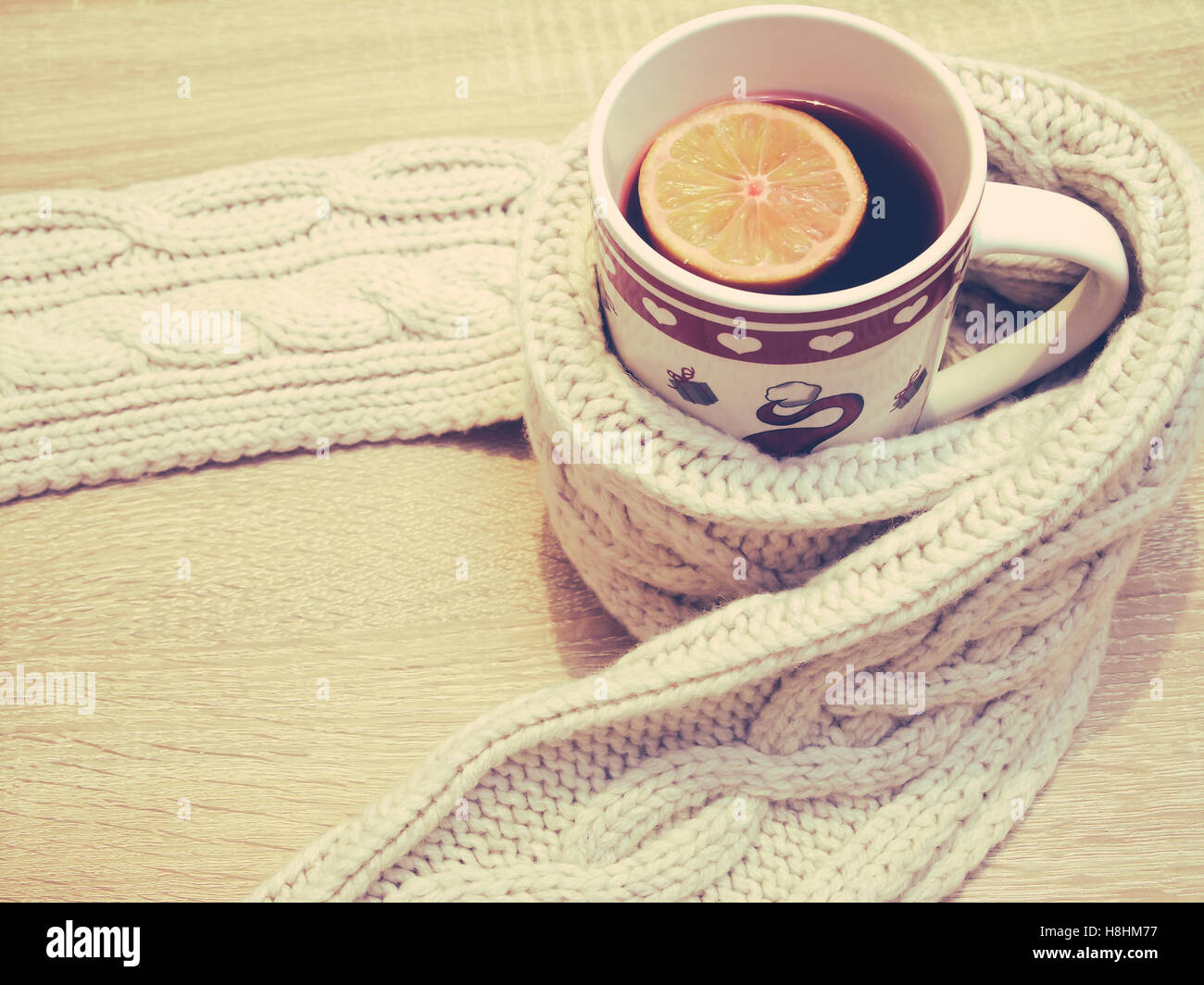 Cup of hot tea with lemon dressed in warm winter scarf Stock Photo