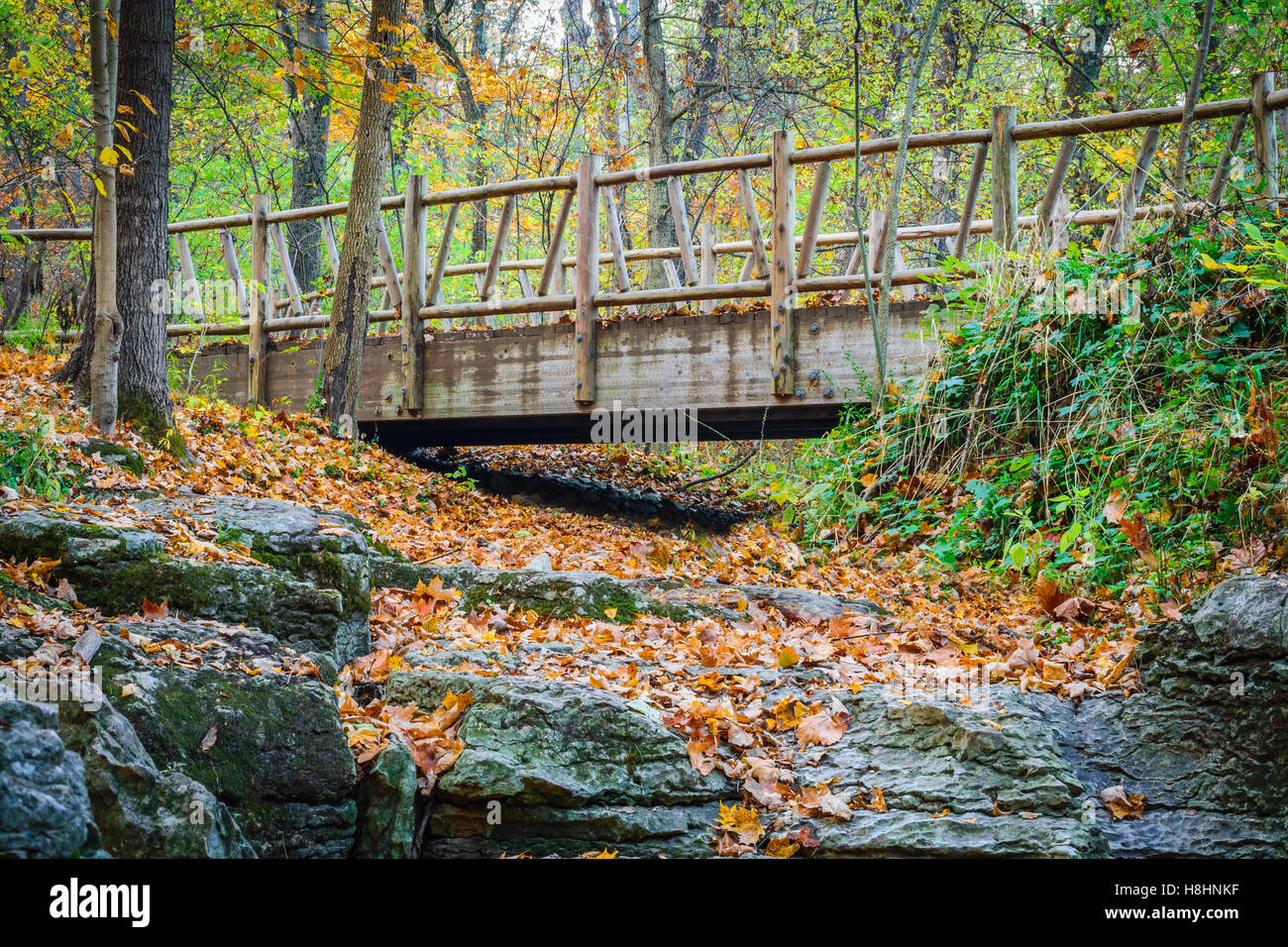 Trail bridge crossing a dry stream with stone creek bed. Stock Photo