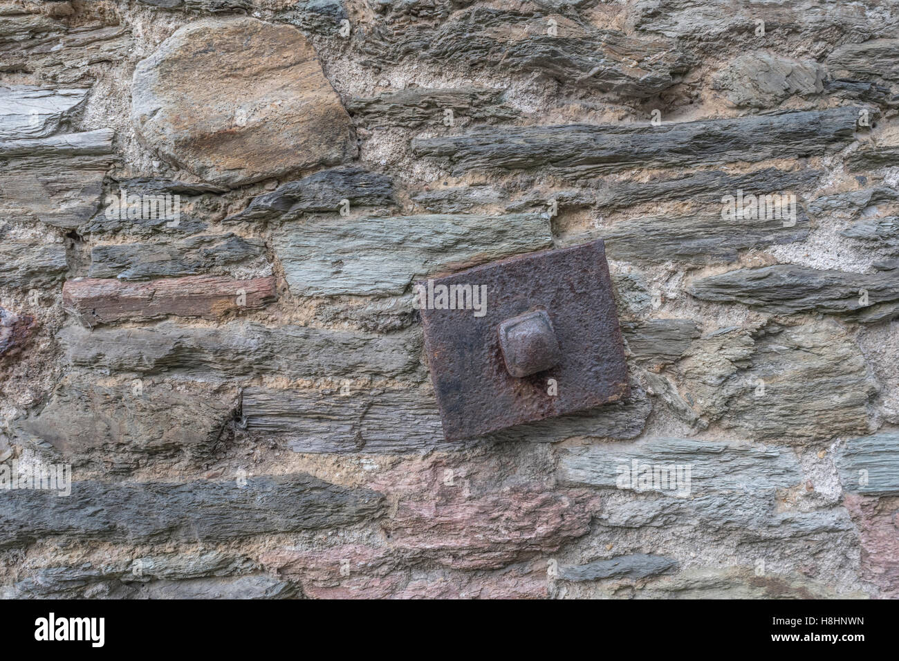 Old stone wall with rusty square bracing plate Stock Photo - Alamy