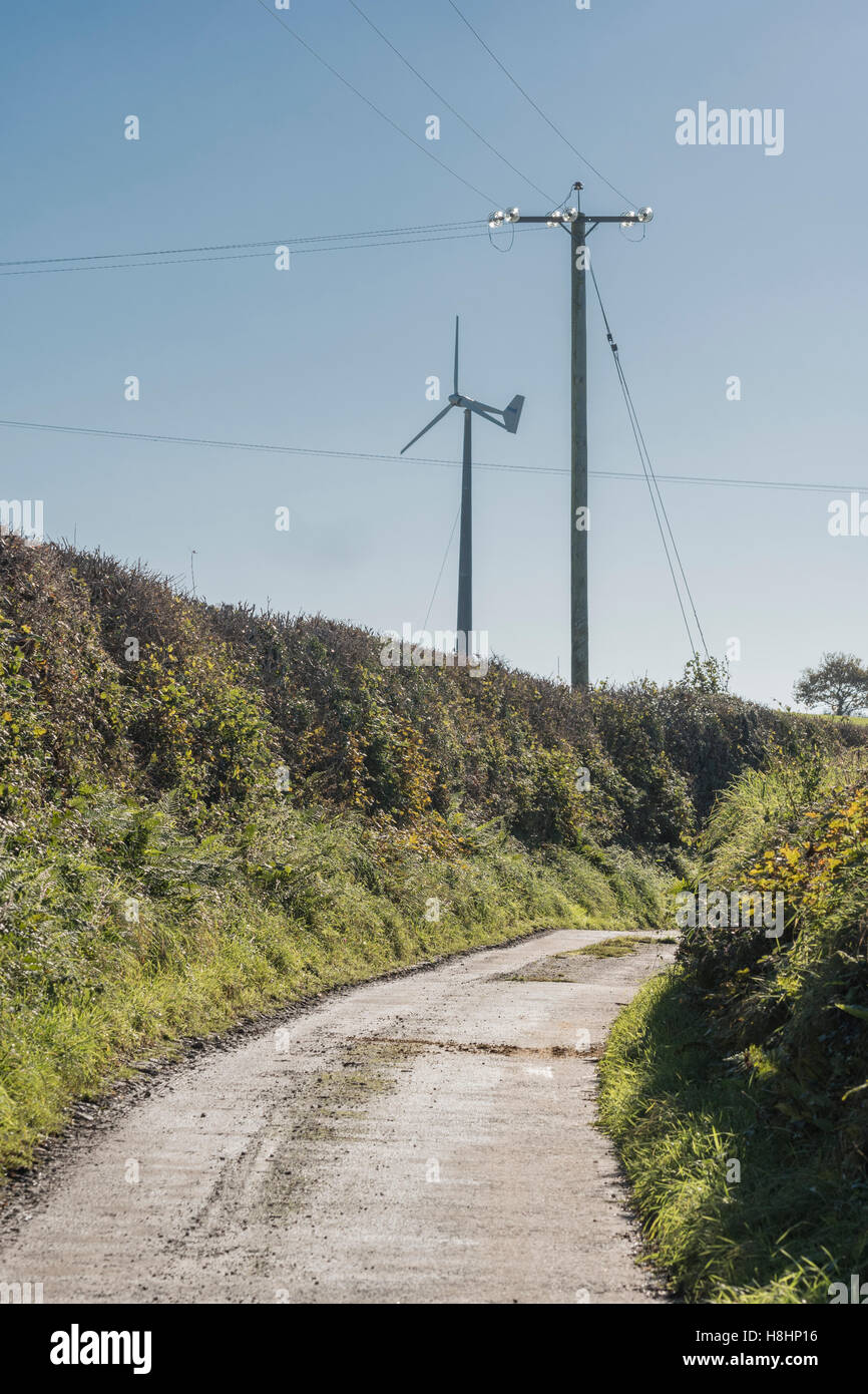 Wind turbine / wind generator  and electricity distribution post on a country lane. UK landscape with wind turbine. Stock Photo