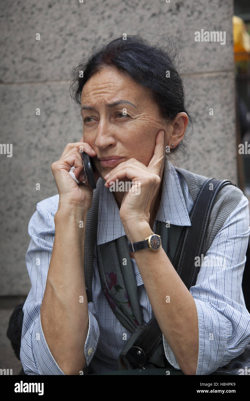 Woman has a serious talk on her cell phone in Pershing Square in Manhattan, NYC. Stock Photo