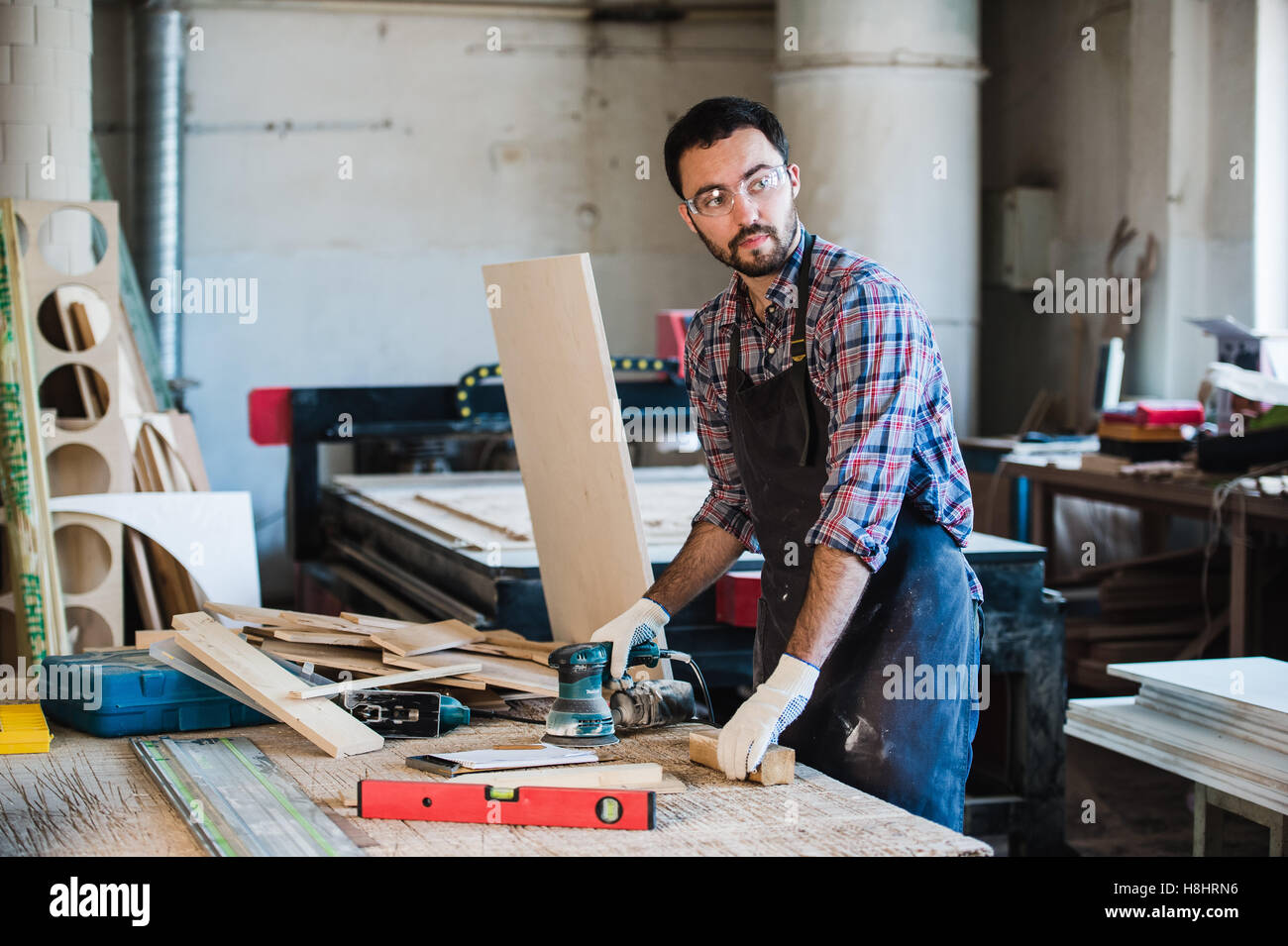 Worker grinds the wood of angular grinding machine Stock Photo