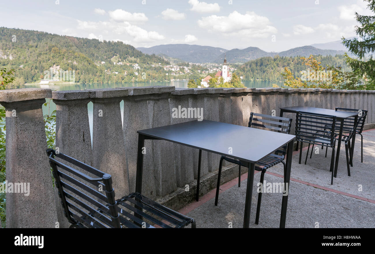 outdoor cafe tables with above view over lake Bled, Alps, island and Church of the Assumption in Slovenia Stock Photo