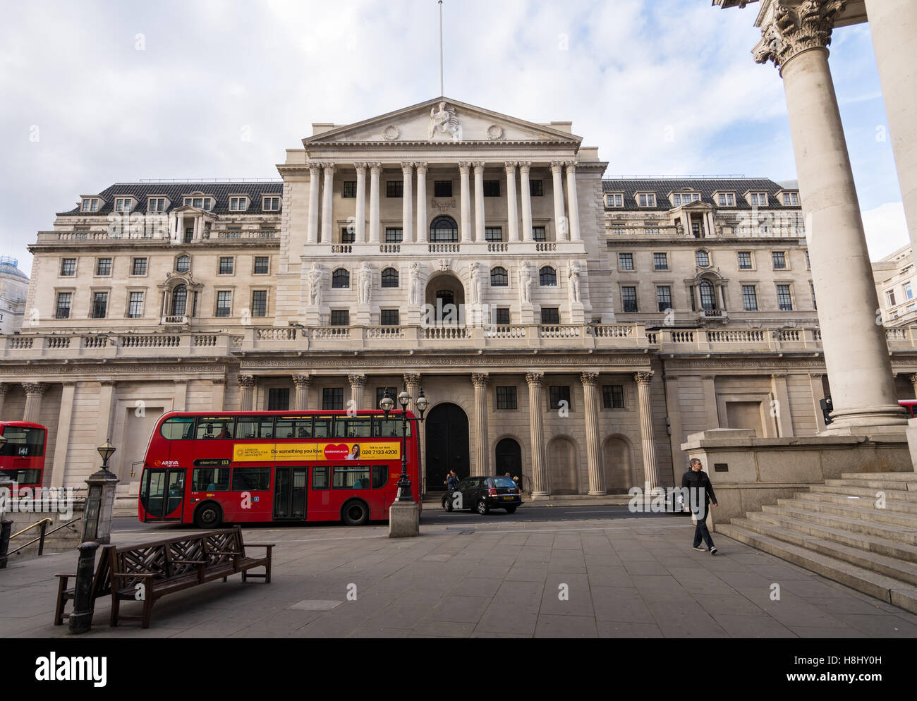 Front view of the Bank of England, Uk's Central Bank with iconic red double-decker London bus in the foreground. Stock Photo