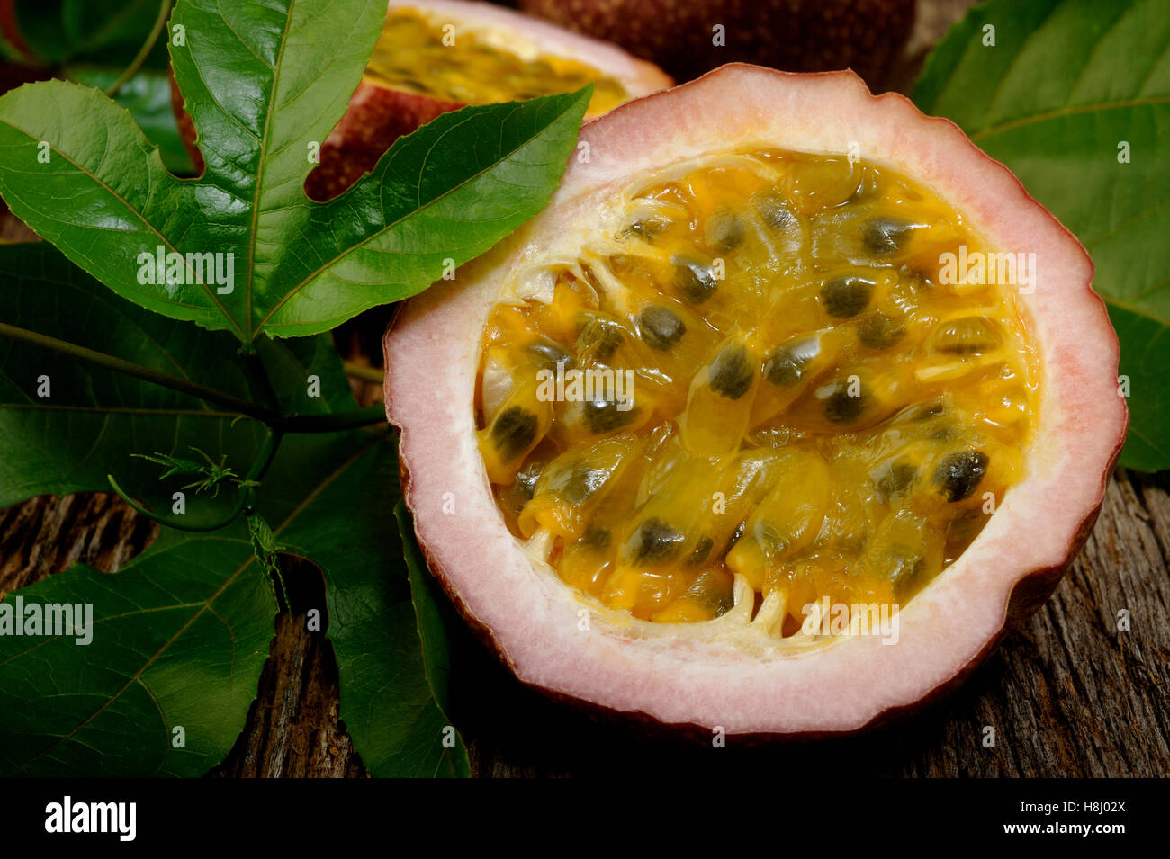 Passion fruits with leaves on wooden background Stock Photo