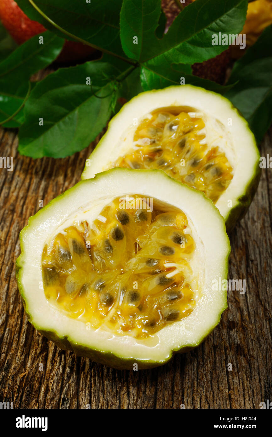 Passion fruits with leaves on wooden background Stock Photo