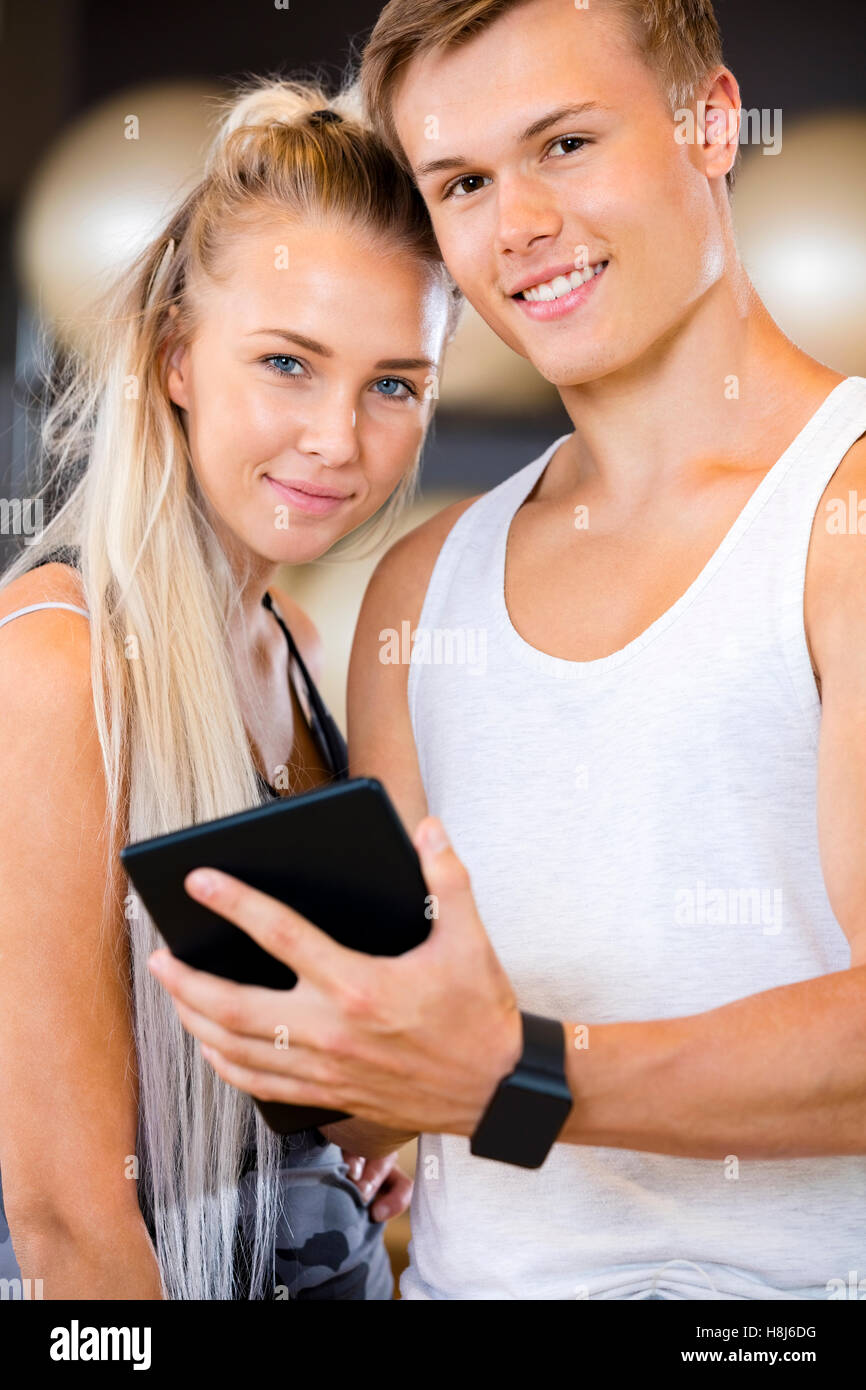 Confident Fit Couple With Digital Tablet Standing In Gym Stock Photo