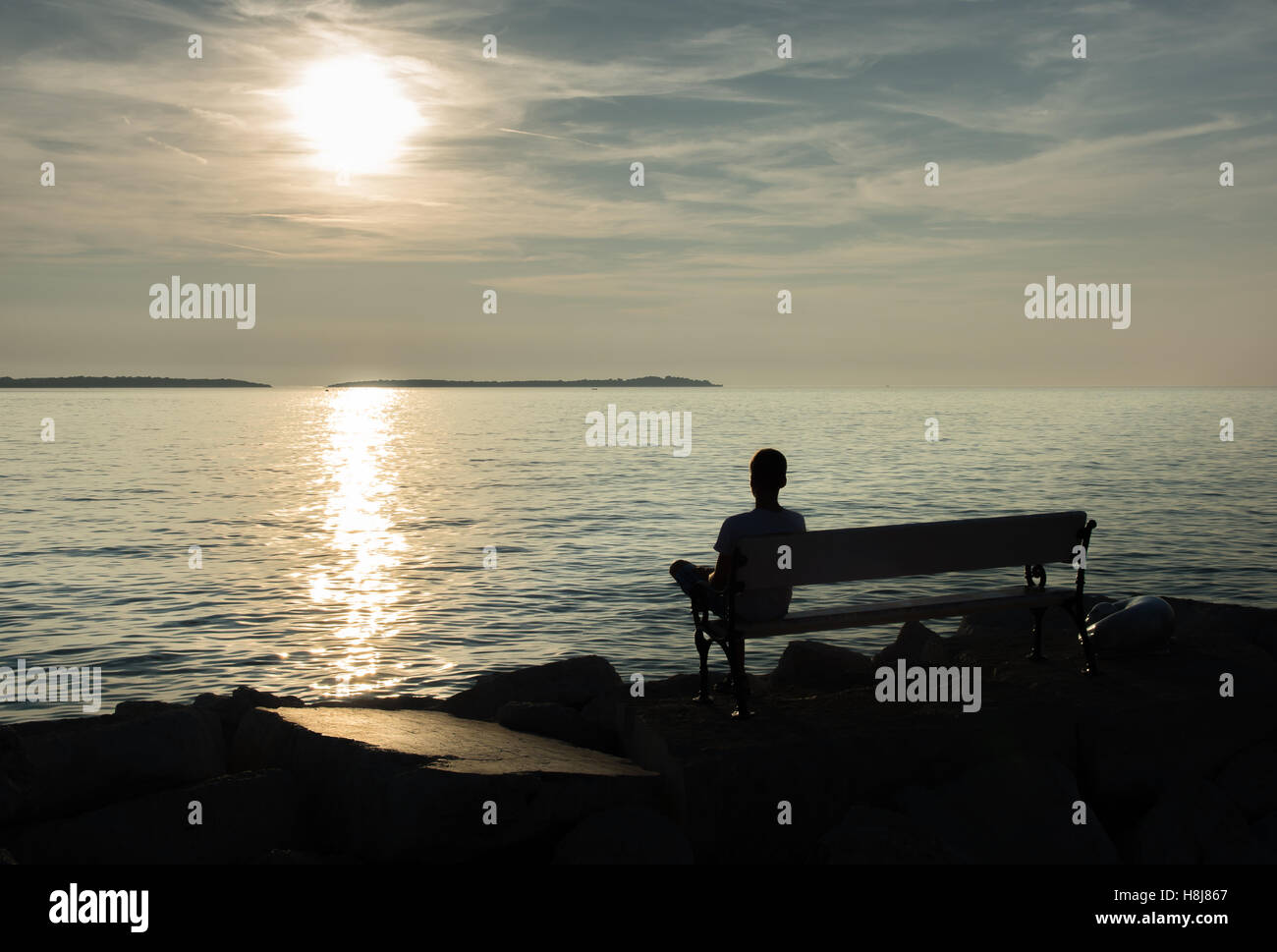 Lonely Single Boy sitting on Bench at Coast Stock Photo - Alamy