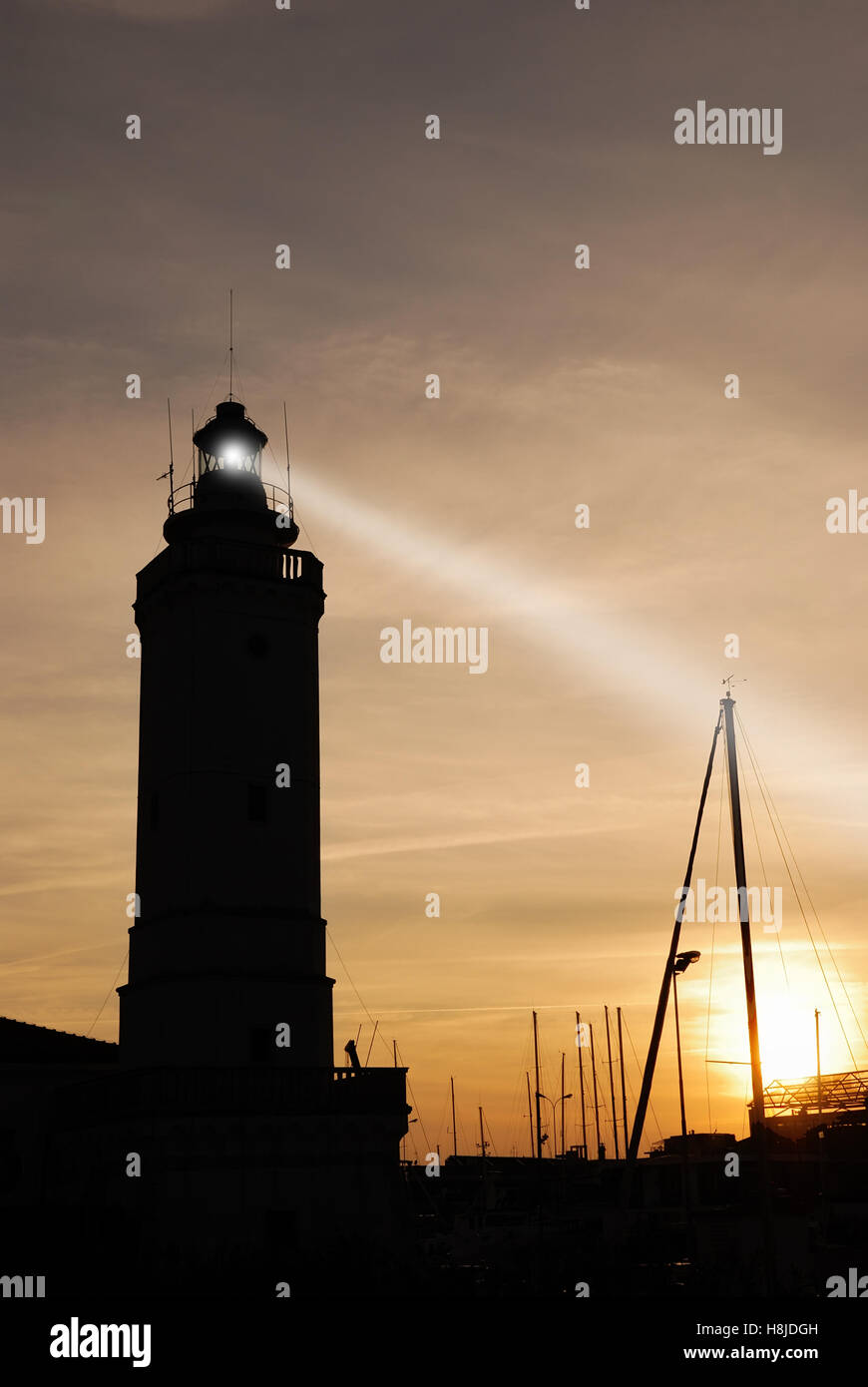 lighthouse at sunset on the port with cloudy sky Stock Photo