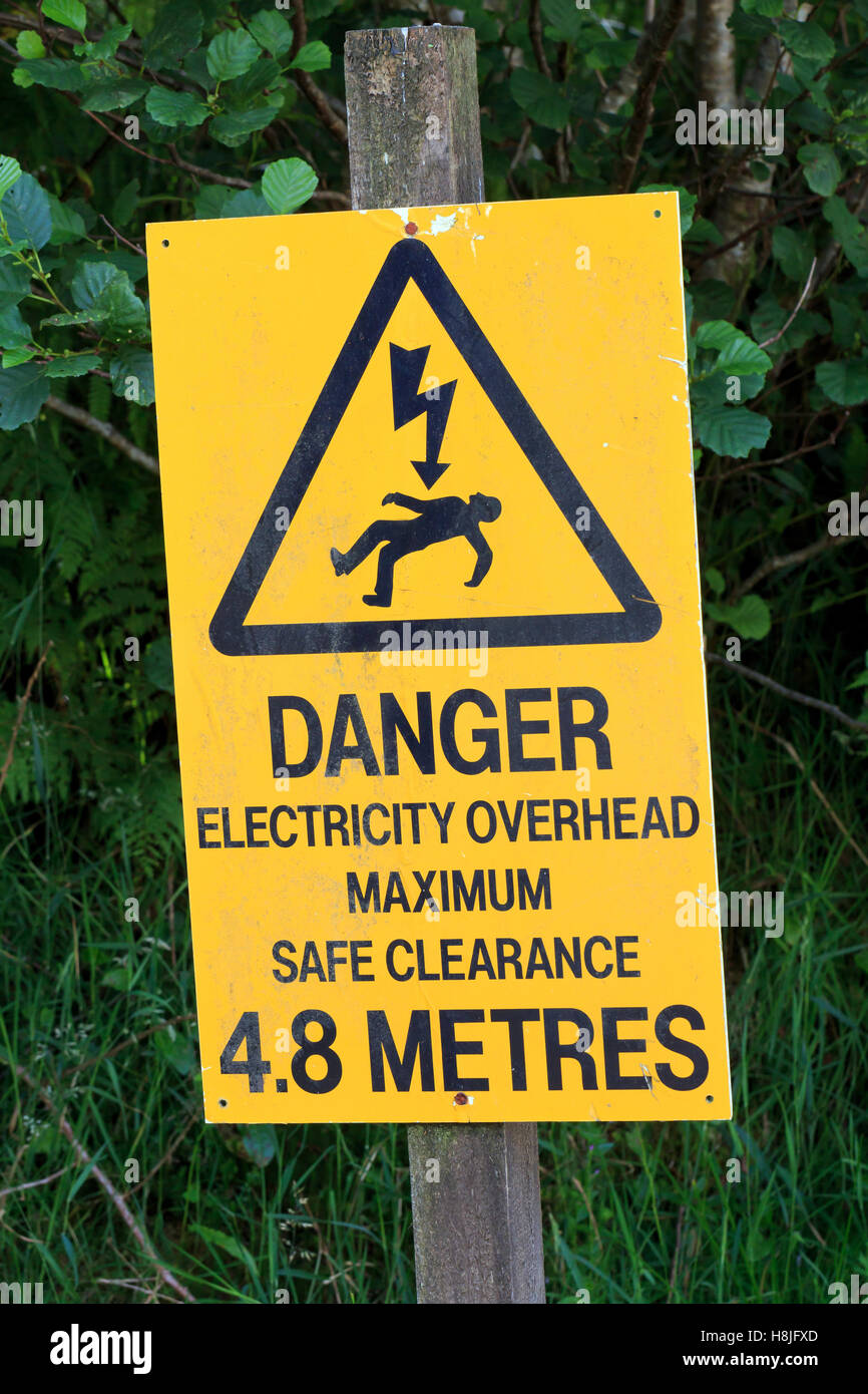 Yellow sign warning of danger electricity overhead Stock Photo