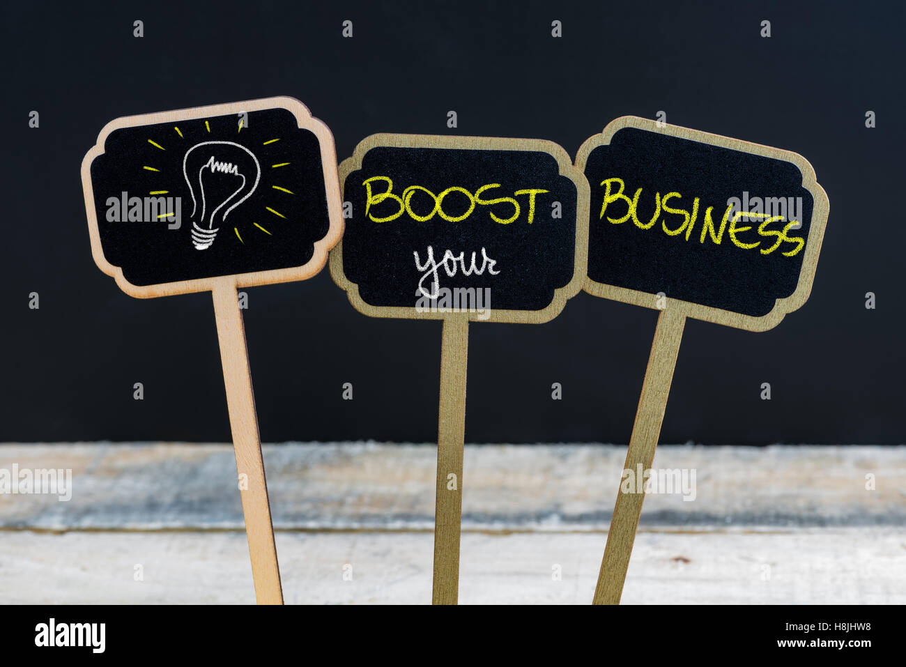 Concept message BOOST YOUR BUSINESS and light bulb as symbol for idea written with chalk on wooden mini blackboard labels Stock Photo