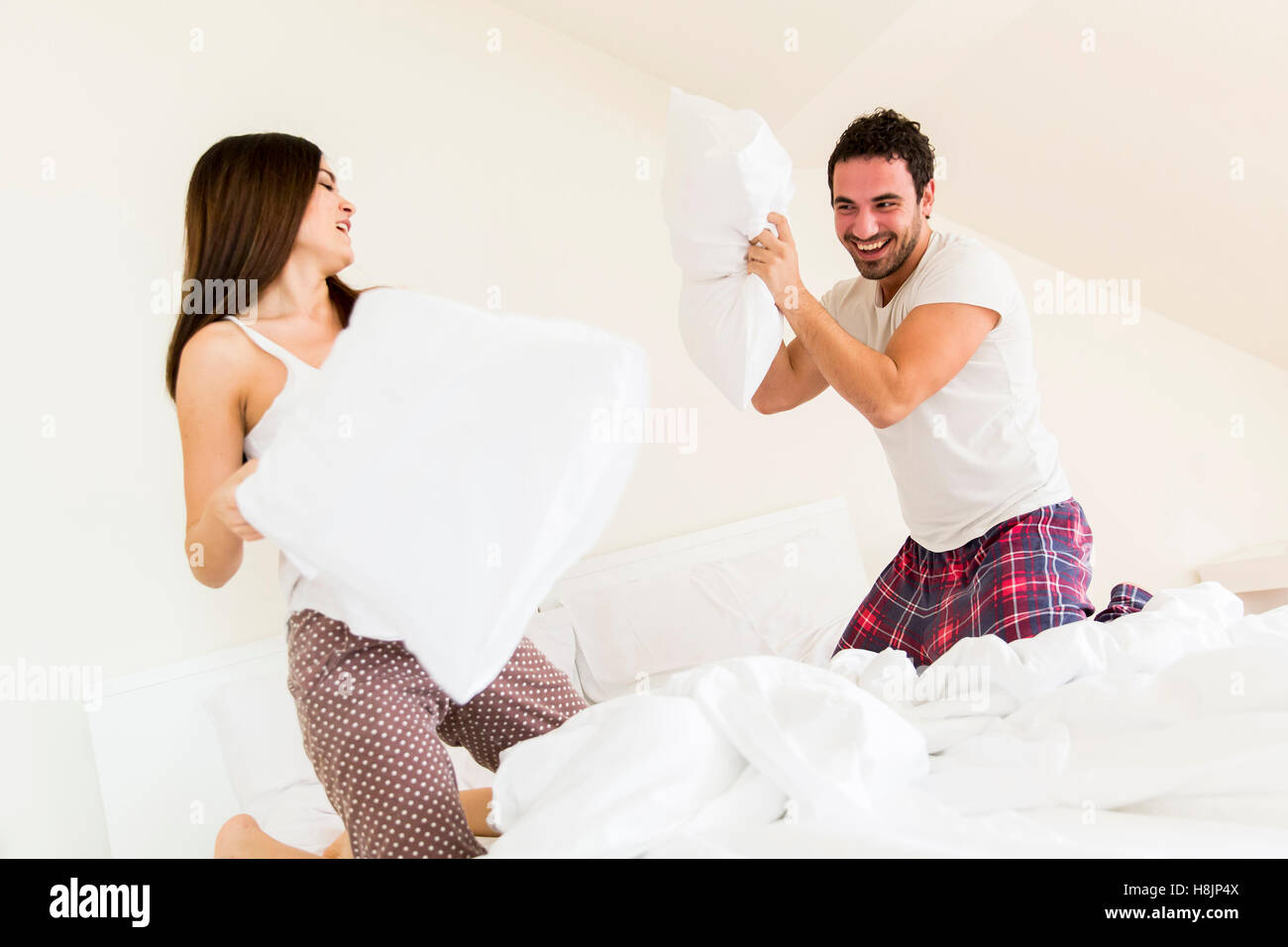 Couple having fun with a pillow fight in bed Stock Photo