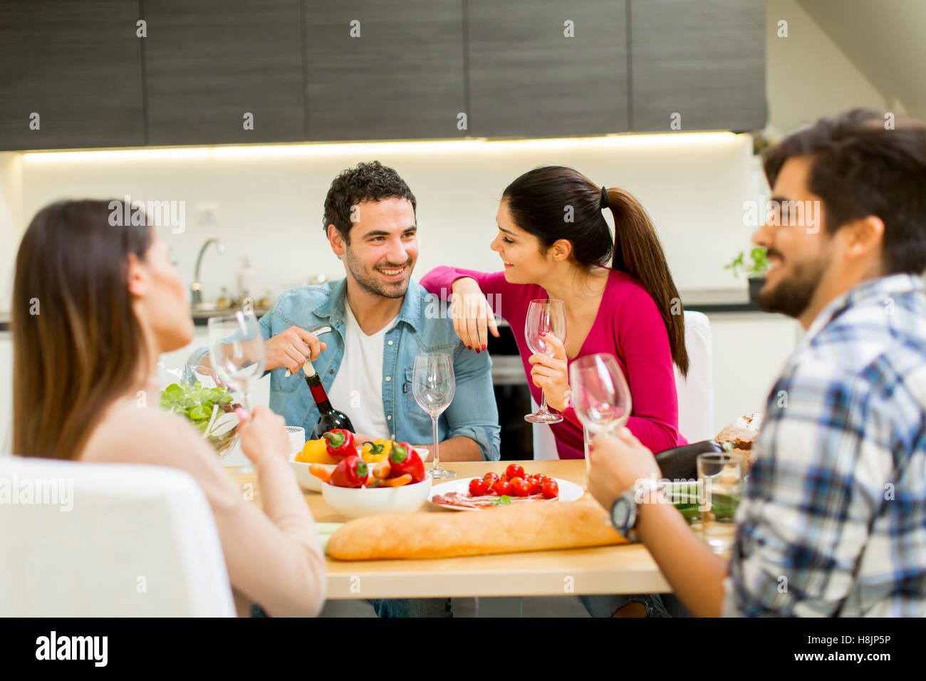 Group of happ young people sitting by the table eating and drinking red wine Stock Photo Alamy