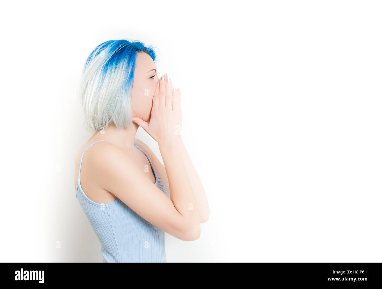 Young teen woman hipster style and blue hair profile screaming with hands on face, isolated on white Stock Photo