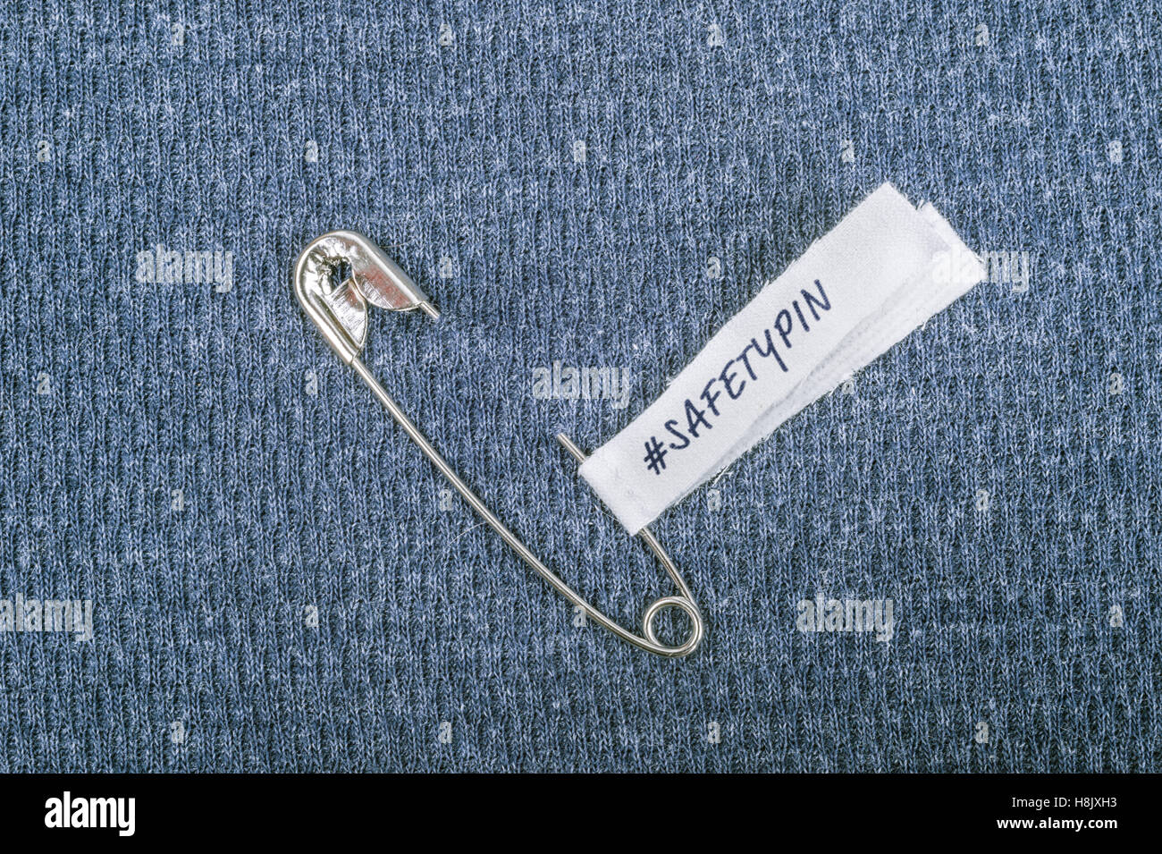 Safety pin on clothes with label #Safetypin as a symbol of