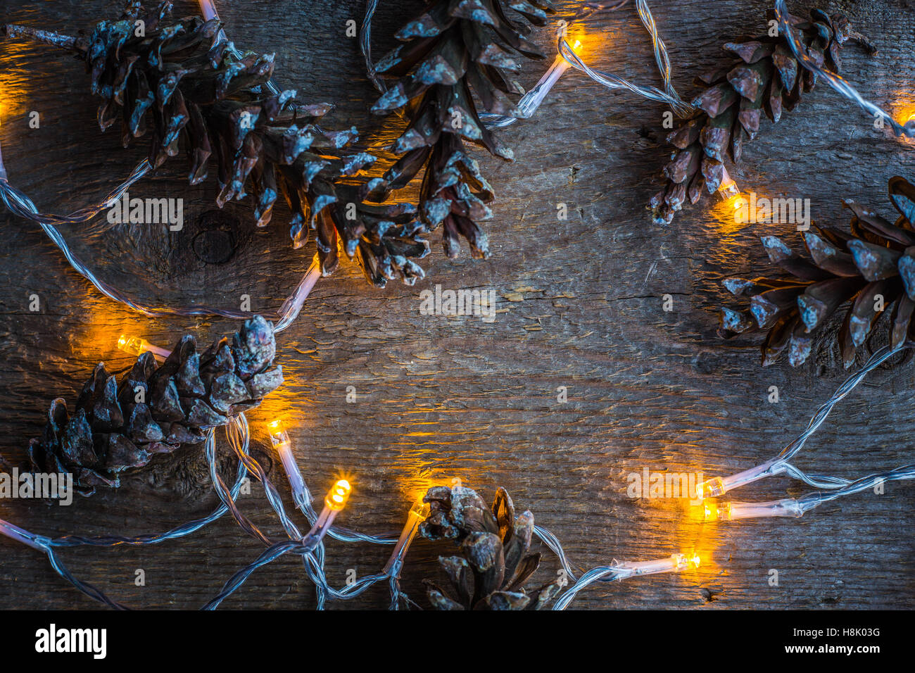 Christmas lights and pine cones on wooden rustic background Stock Photo ...