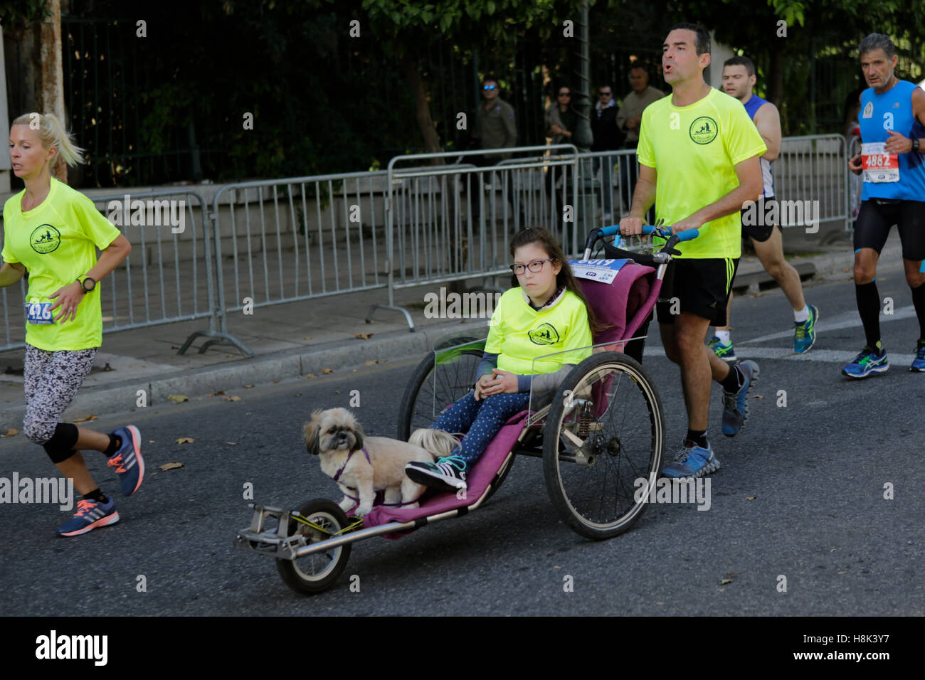 Athens, Greece. 13th Nov, 2016. A runner pushes a girl and a dog in a wheel chair. Thousands of people from all over the world took part in the 2016 Athens Marathon the Authentic, which starts in the town of Marathon and is ending in Athens, the route, which according to legend was first run by the Greek messenger Pheidippides in 490 BC. © Michael Debets/Pacific Press/Alamy Live News Stock Photo