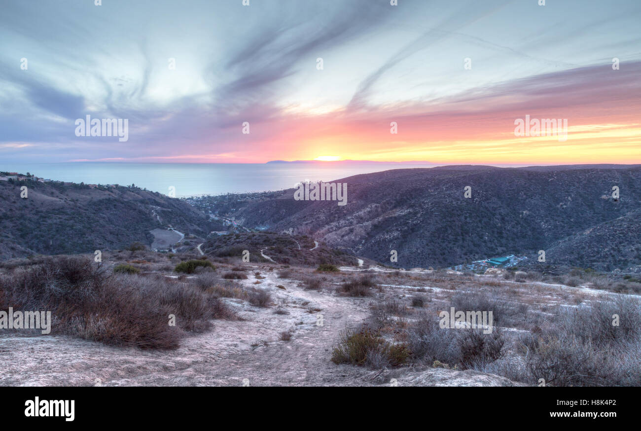 Laguna Canyon Road leading to the ocean from Top of the World hiking trail in Laguna Beach at sunset Stock Photo