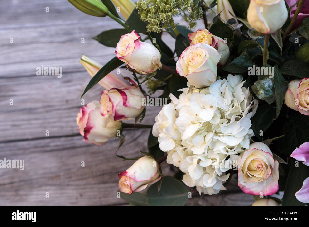 Wedding bouquet of white and pink flowers including roses, hydrangea, star gazer lilies and queen annes lace on a rustic table i Stock Photo