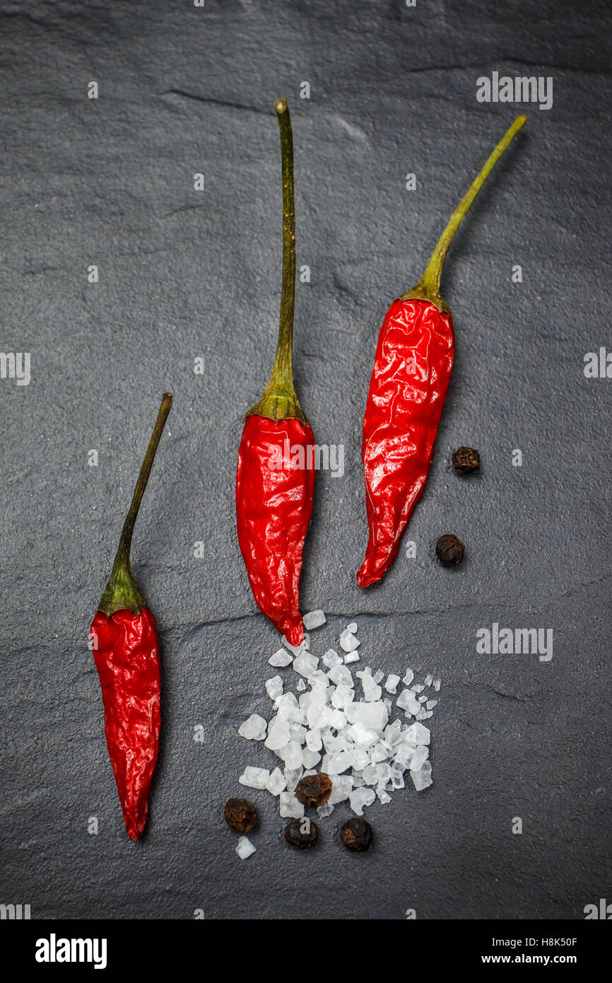 Chili with black pepper and salt on rustic stone background. Overhead