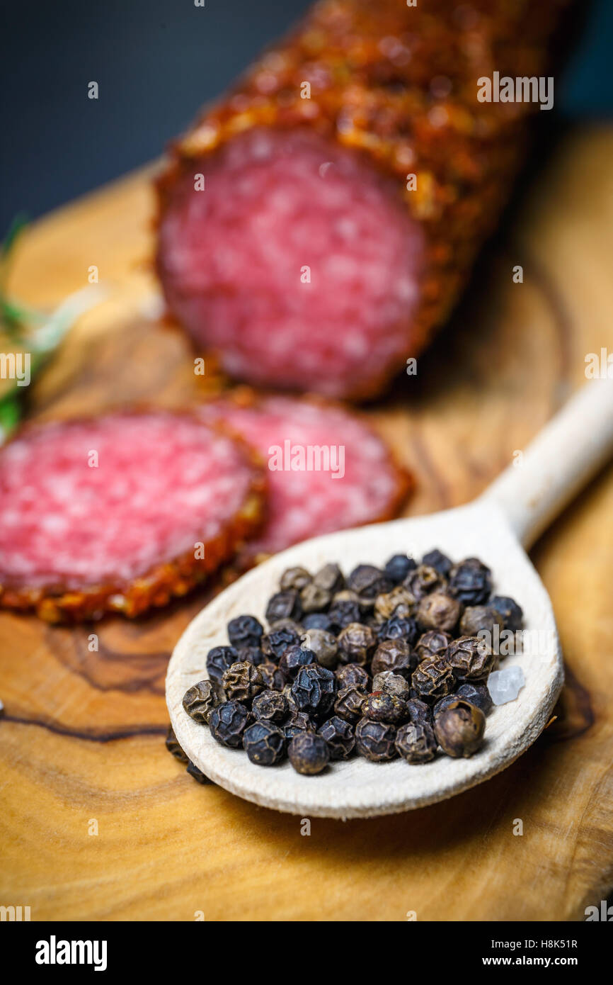 dried salami crusted in ground red pepper on dark background Stock