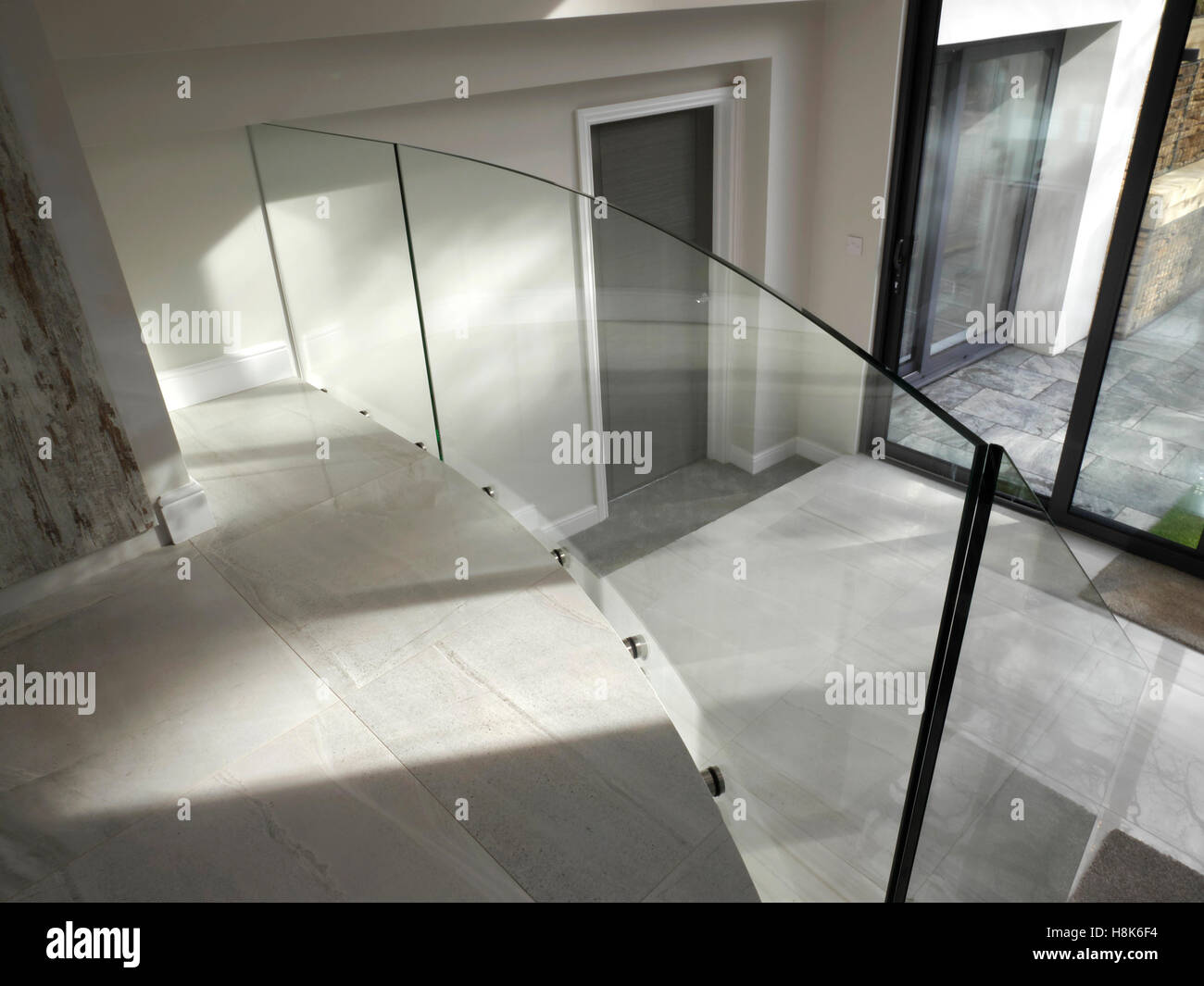 Contemporary split level home using toughened circular glass as a panel divider between ground and lower ground floors to provide a light safe airy environment Stock Photo