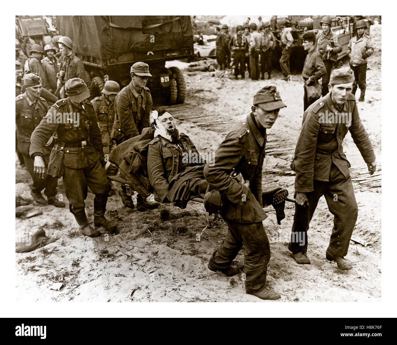 NAZI WOUNDED PRISONERS D-Day Operation Overlord WW2 German POW's carry wounded comrades to landing craft on a Normandy beach with American troops behind June1944 Northern France Stock Photo