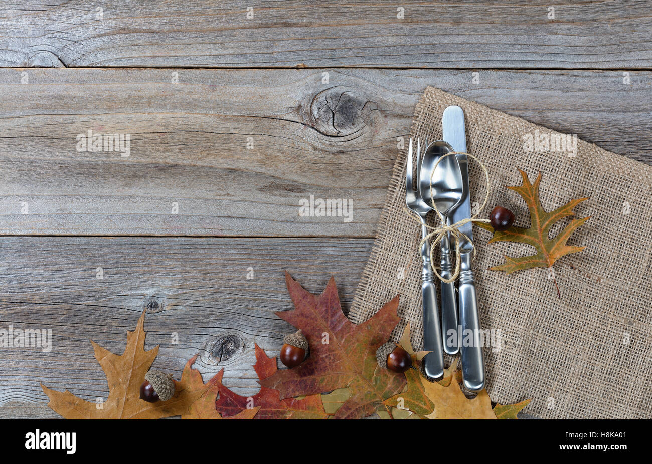Fall dinner place setting for Thanksgiving holiday in horizontal layout on rustic wooden boards. Stock Photo