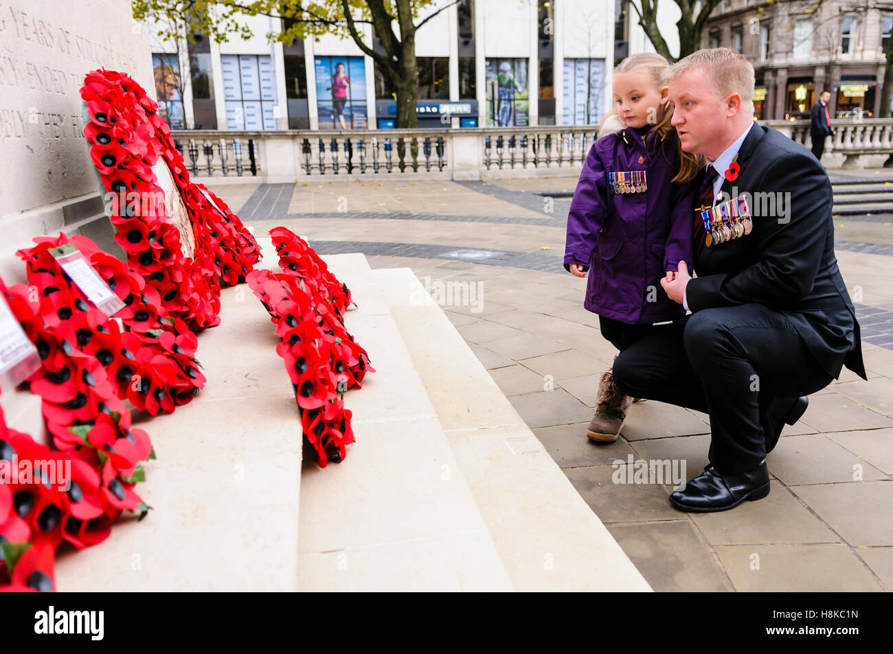 Belfast, Northern, Ireland. 13th Nov, 2016. A soldier wearing medals and his daughter look at the poppy wreaths. Remembrance Sunday service at Belfast City Hall Cenotaph. Credit:  Stephen Barnes/Alamy Live News Stock Photo