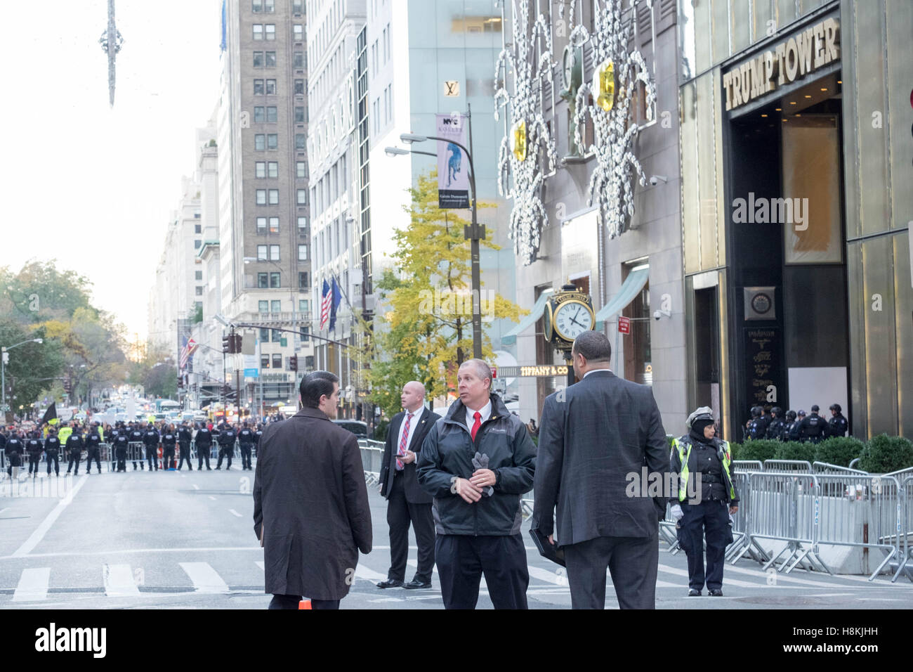 New York, USA. 13th November, 2016. NYC Police Commissioner New York, USA. 13th November, 2016. James P. O'Neill and other high-ranking NYPD officials convene a meeting on 5th Avenue, New York City, in front of the barricaded Trump Tower, as protestors march in the background. Credit:  barbara cameron pix/Alamy Live News Stock Photo