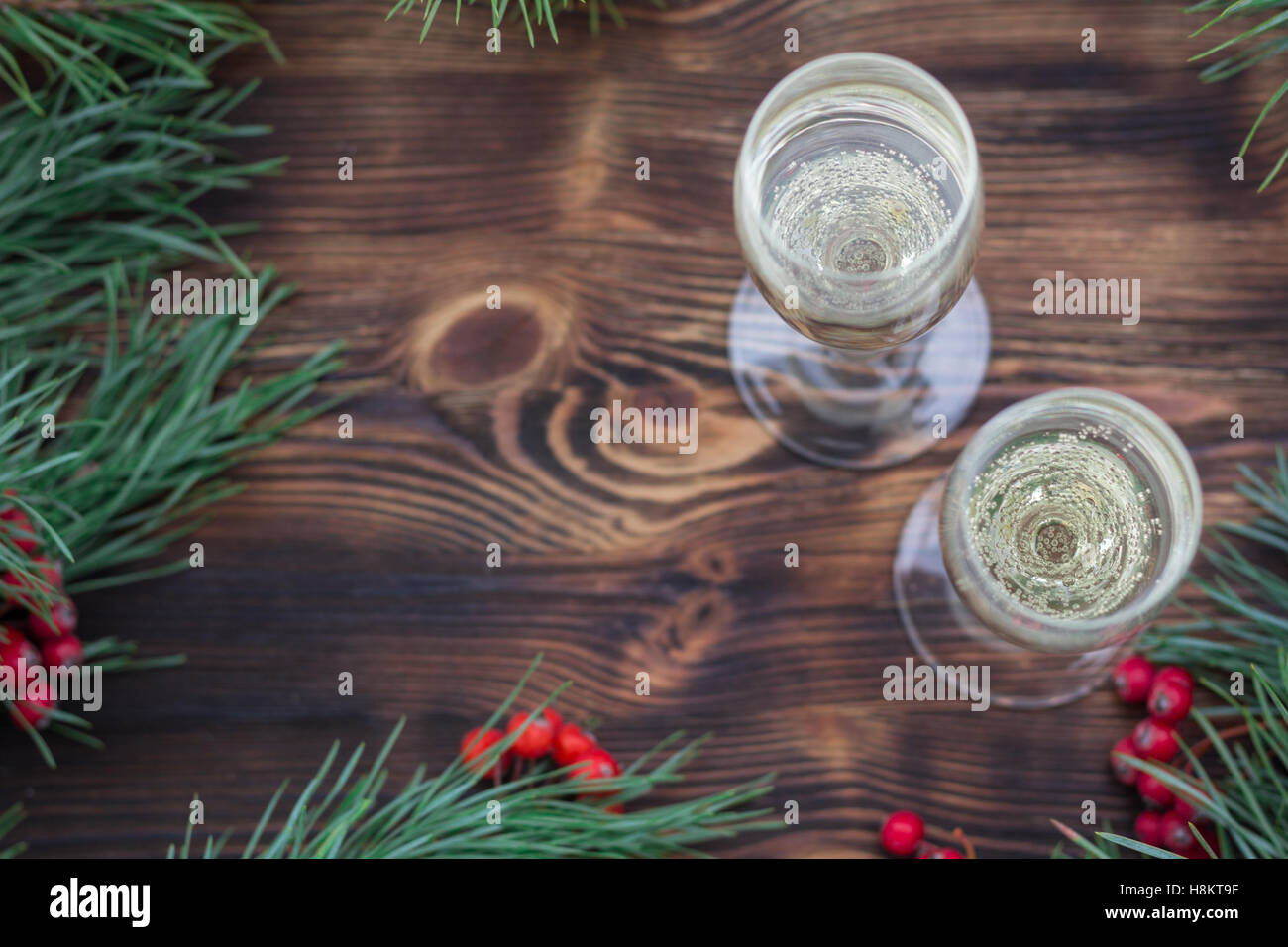 Christmas and New Year seasonal composition with pine tree branches, two glasses of champaign and red rowan berries Stock Photo