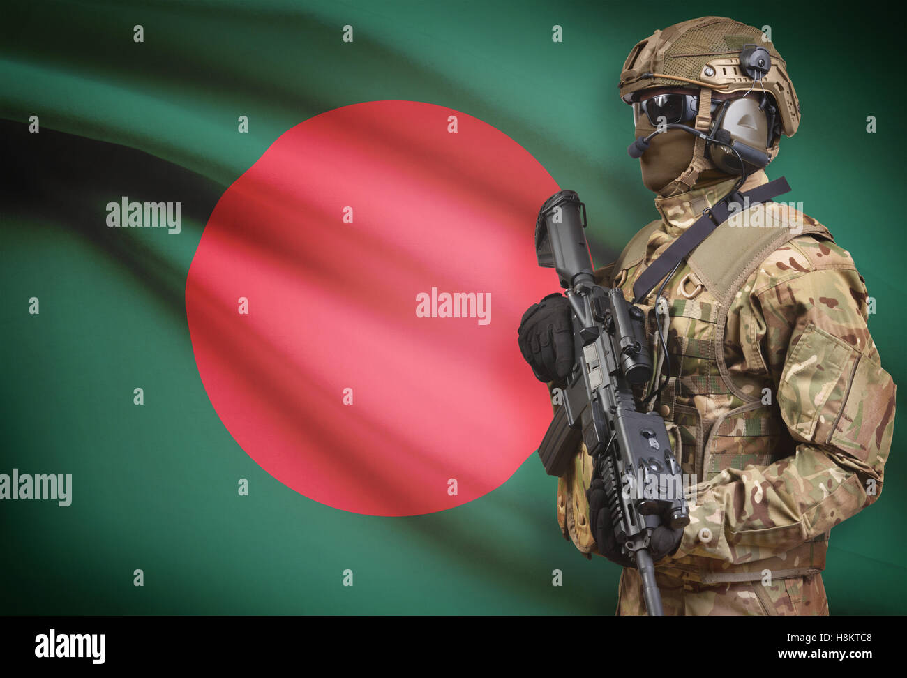 Soldier in helmet holding machine gun with national flag on background