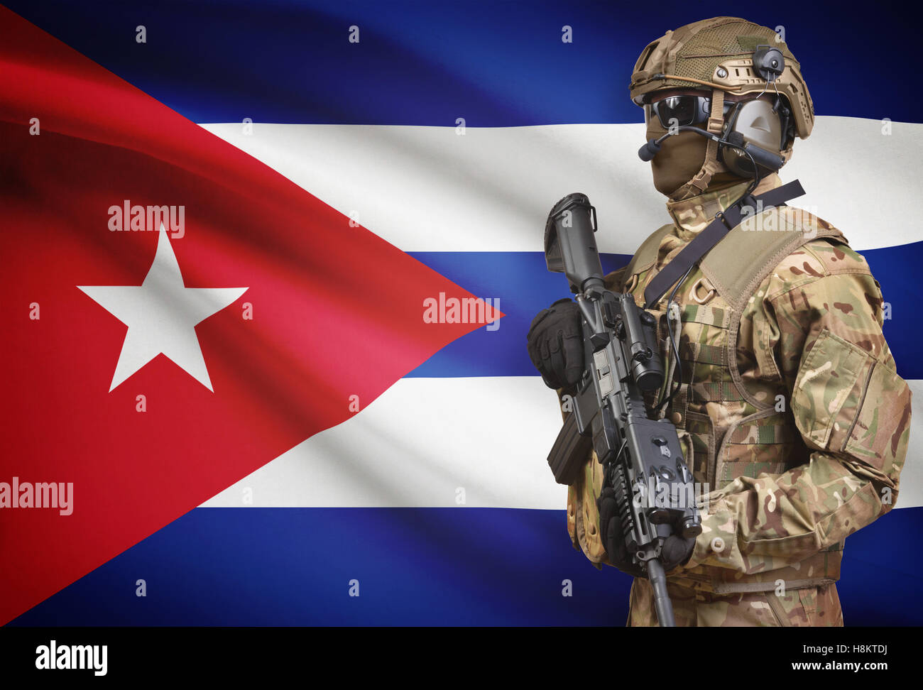 Soldier in helmet holding machine gun with national flag on background - Cuba Stock Photo
