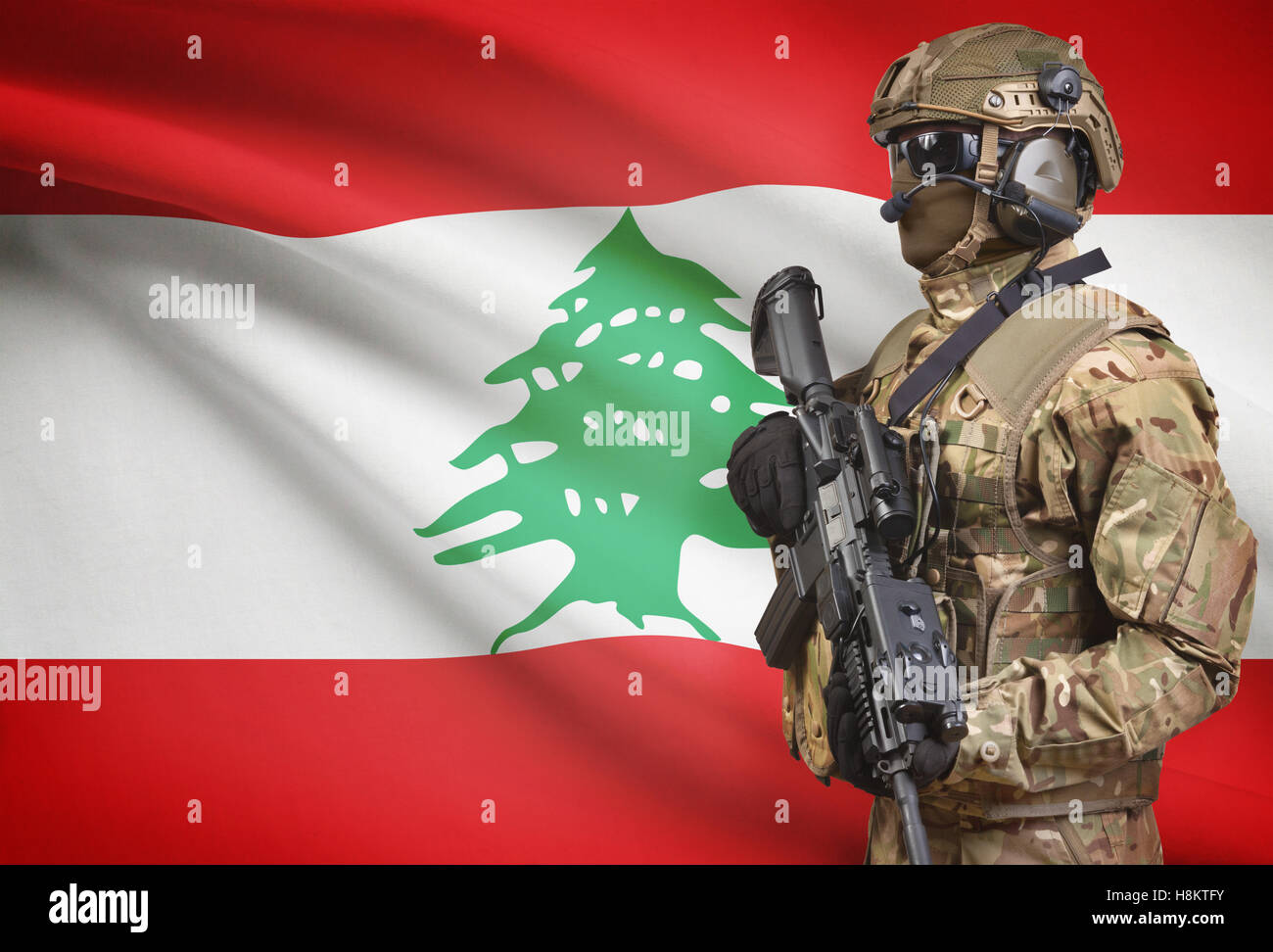 Soldier in helmet holding machine gun with national flag on background