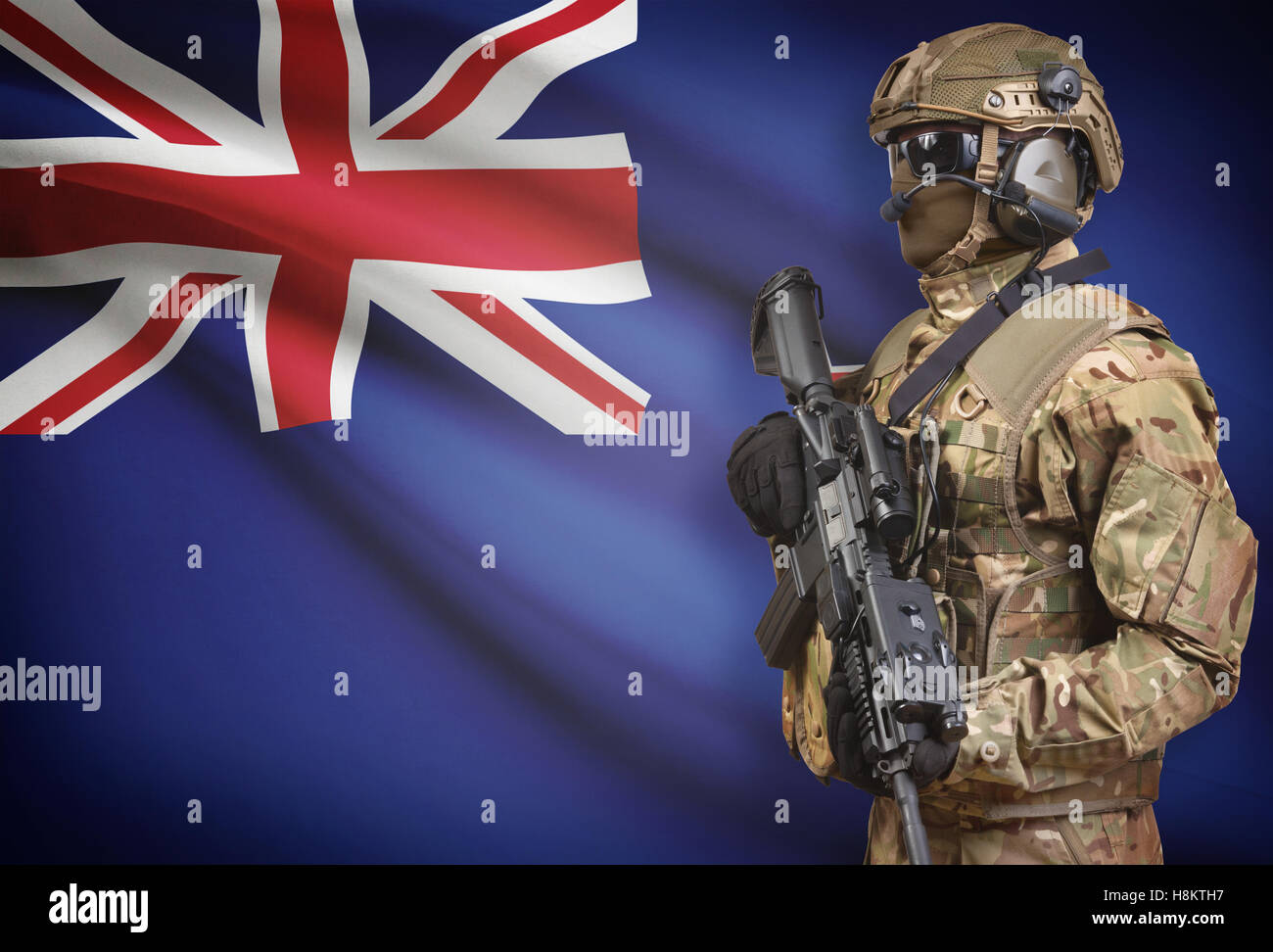 Soldier in helmet holding machine gun with national flag on background - New Zealand Stock Photo