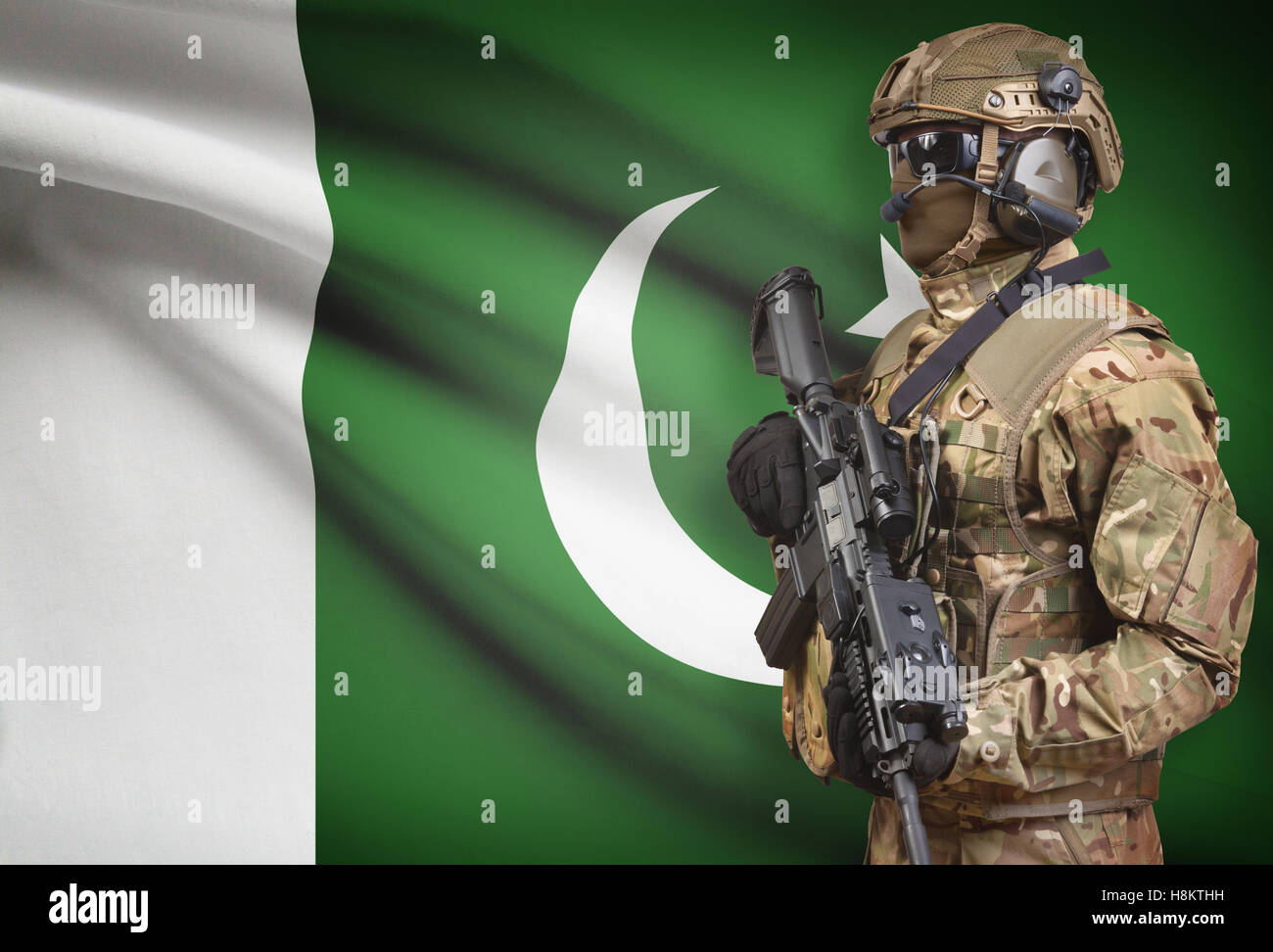 Soldier in helmet holding machine gun with national flag on background