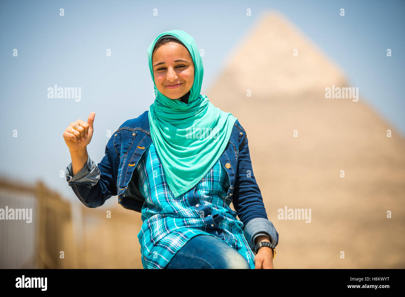 Cairo, Egypt Egyptian woman sitting in front of the Great Pyramids of Giza that are in the background. This particular one is Th Stock Photo