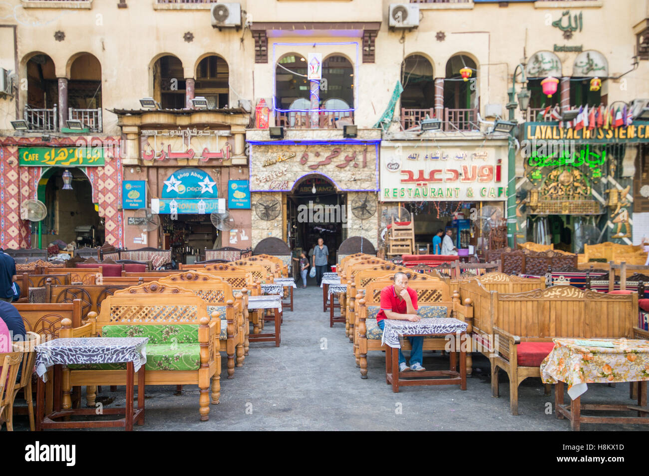 Cairo, Egypt. Man sitting alone in a sitting area surrounded by different shop signs in the outdoor bazaar/ flea market Khan el- Stock Photo