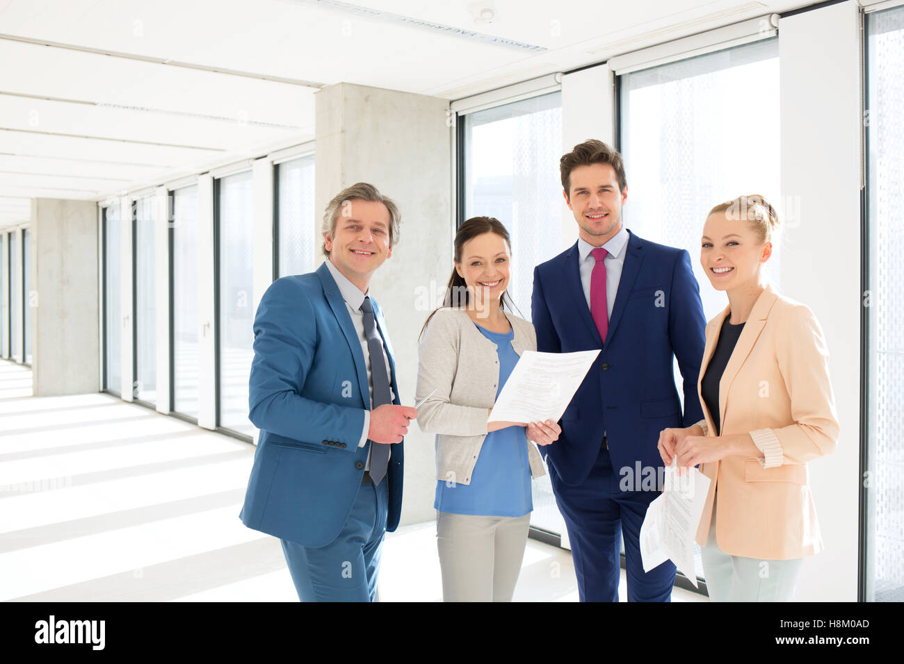 Portrait of smiling business people with documents in new office Stock ...