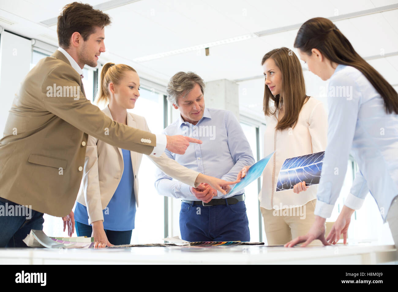 Male design professional with team discussing at table in new office Stock Photo