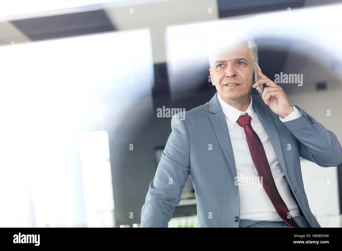 Mature businessman talking on mobile phone in board room Stock Photo