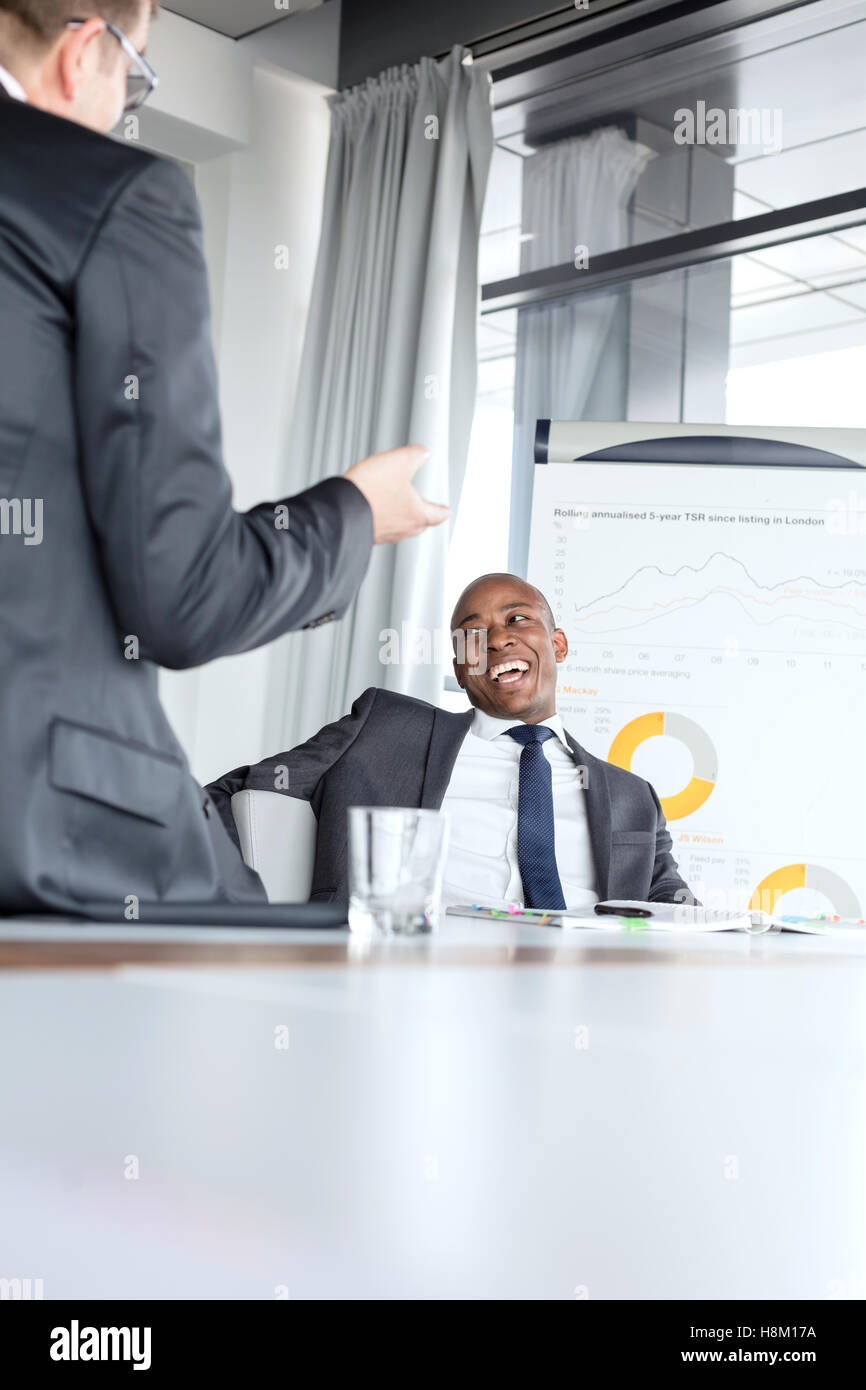 Cheerful young businessman talking with male colleague in board room Stock Photo