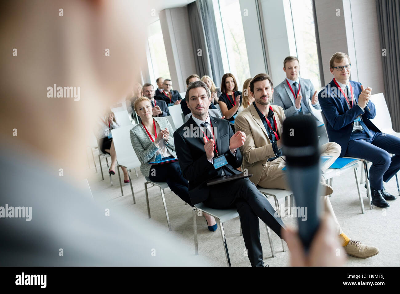 Business people applauding for public speaker during seminar at convention center Stock Photo